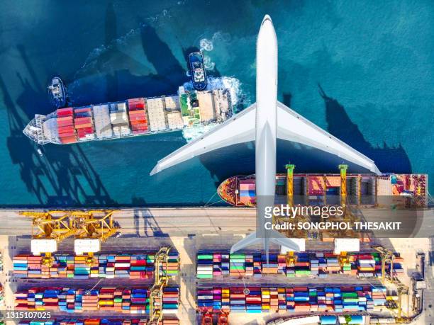 aerial view/an aircraft flying over a port carrying containers onto a cargo ship for delivery to the country of destination. - air cargo stock pictures, royalty-free photos & images