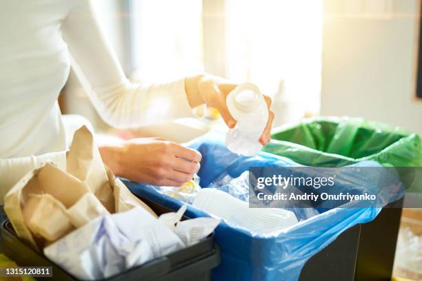 young woman sorting garbage in kitchen. - orchestre photos et images de collection