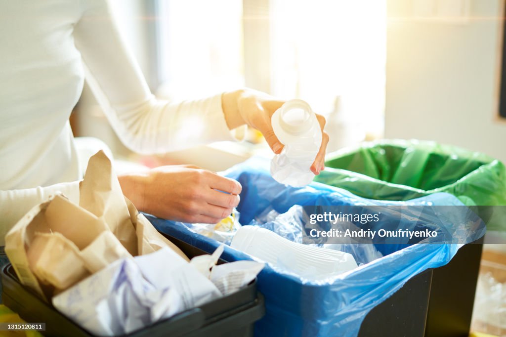Young woman sorting garbage in kitchen.
