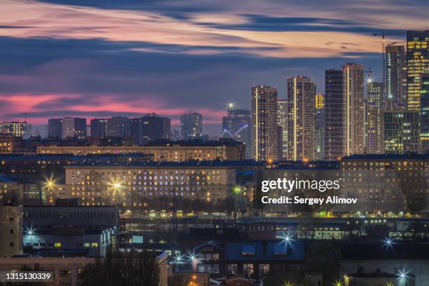 dramatic evening cloudscape over illuminated buildings of city - evolution tower moscow stock pictures, royalty-free photos & images