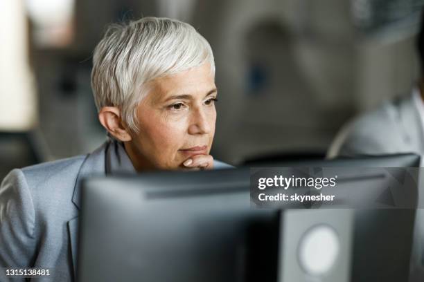 nachdenkliche senior-geschäftsfrau, die am pc im büro arbeitet. - old monitor computer stock-fotos und bilder