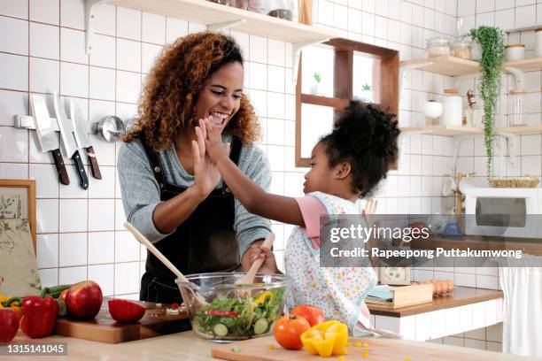 daughter helping mom in the kitchen making a salad at home. - making dinner stock pictures, royalty-free photos & images