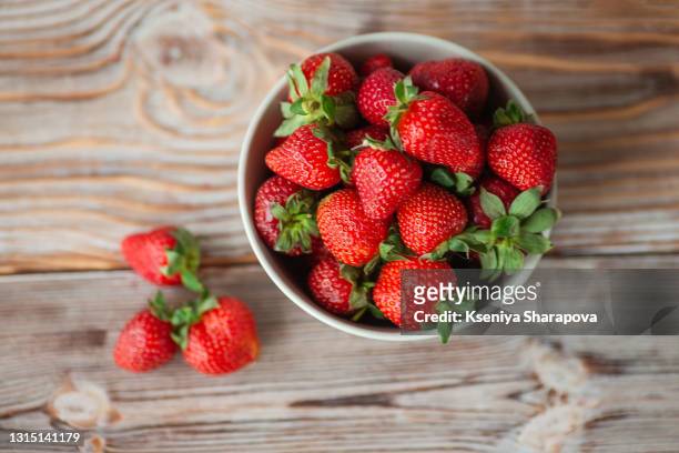 bowl of ripe strawberries on wooden  table - stock photo - strawberry stockfoto's en -beelden