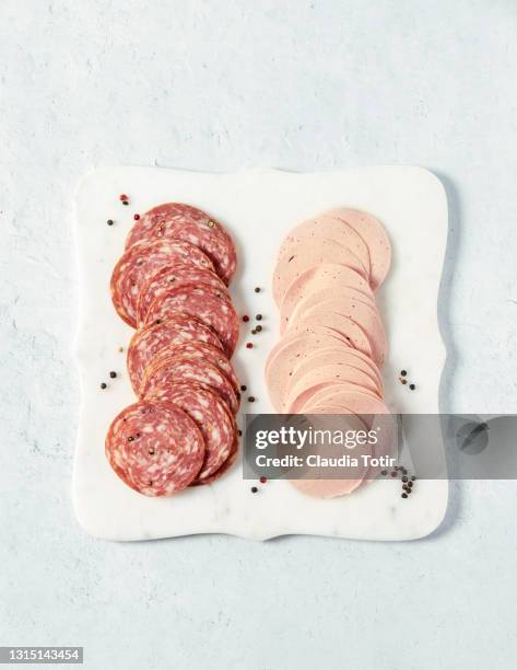 variety of salami on white cutting board - charcutería fotografías e imágenes de stock