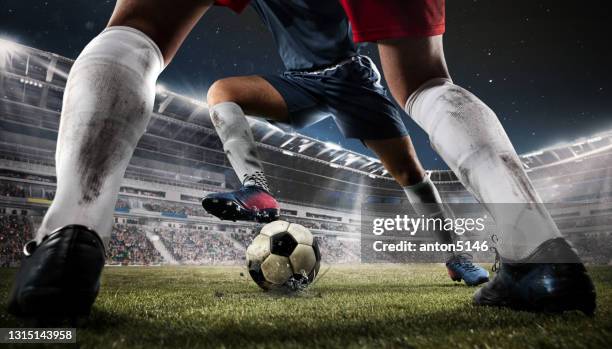 close-up two football or soccer players in action at stadium in flashlights. - kicking stock pictures, royalty-free photos & images