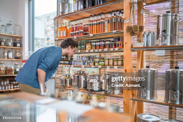 caucasian male costumer in 30's checking the organic goods displayed on the shelves in a sustainable store - mason jar stock pictures, royalty-free photos & images