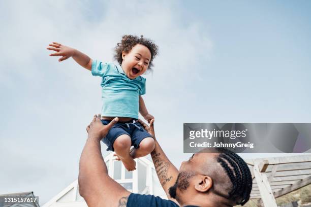 young boy with down syndrome expressing joy in mid-air - disability stock pictures, royalty-free photos & images
