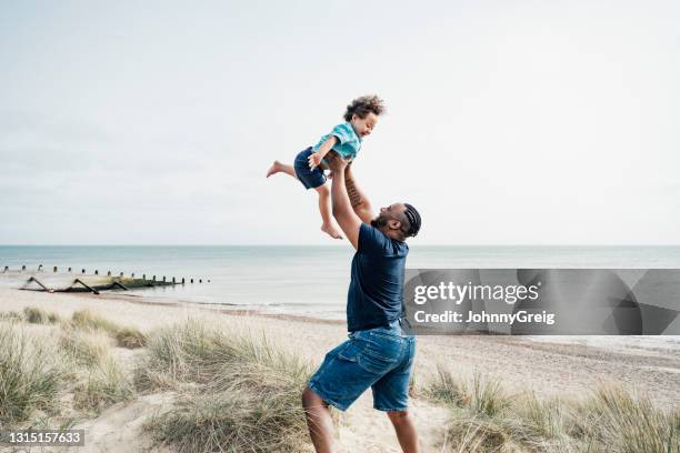 father and son enjoying vacation playtime at camber sands - familie am strand stock pictures, royalty-free photos & images