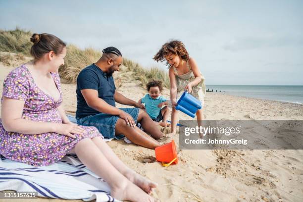 vielfältige junge britische familie spielt am strand - spring break stock-fotos und bilder