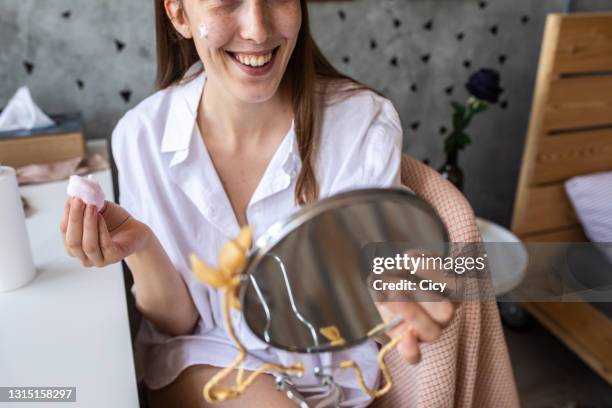 young woman applying face cream at home - woman applying cotton ball stock pictures, royalty-free photos & images