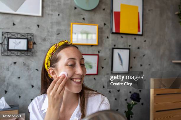 young woman applying face cream at home - woman applying cotton ball stock pictures, royalty-free photos & images