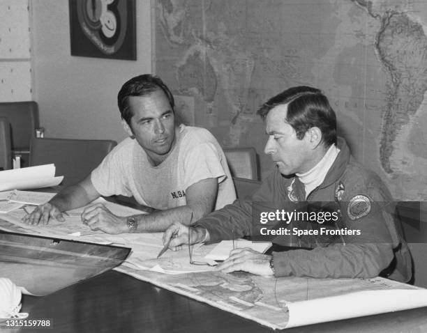 Space Shuttle crew members Robert Crippen and John Young study charts at a briefing on weather condition expected for launch the following day from...