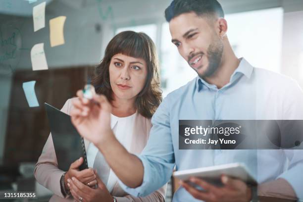 aufnahme einer jungen geschäftsfrau und geschäftsfrau mit einem digitalen tablet während einer brainstorming-sitzung in einem modernen büro - content stock-fotos und bilder