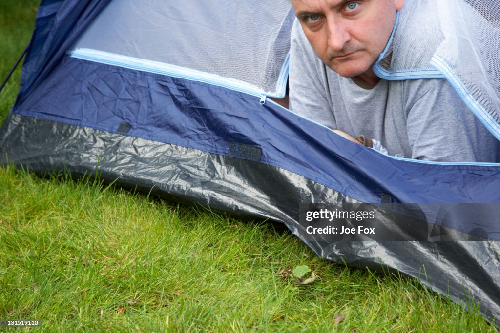 Grumpy old man sticking head out of tent door