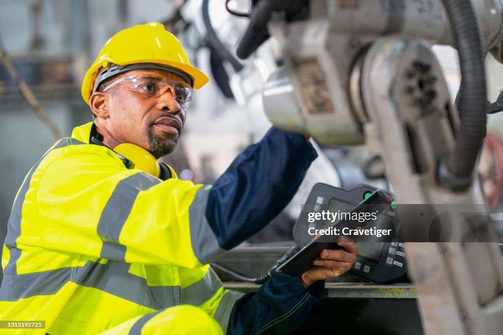 Senior inspector working in robot factory . He check the robot before work in process.
