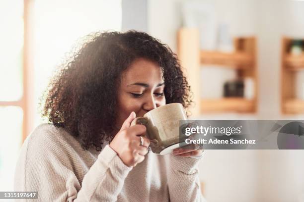 schuss einer jungen frau, die eine tasse kaffee in ihrer küche zu hause trinkt - hot chocolate stock-fotos und bilder