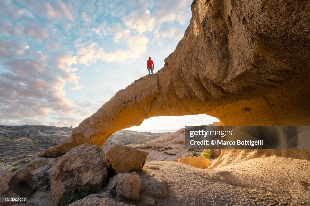 Person standing on top of a natural arch, Canary islands, Spain