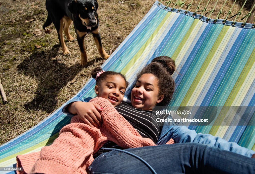 Sisters lying on hammock outdoors in springtime.