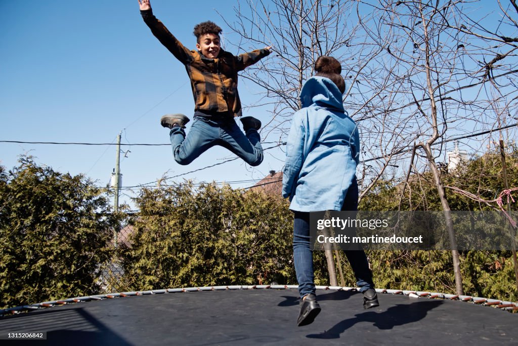 Hermanos saltando en trampolín al aire libre en primavera.