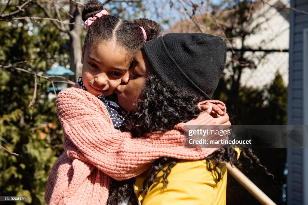 Madre consolando a su hija pequeña al aire libre en primavera.