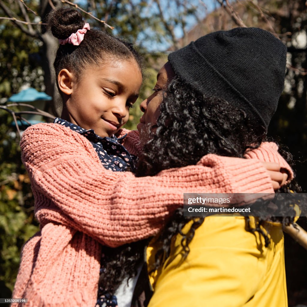 Madre consolando a su hija pequeña al aire libre en primavera.