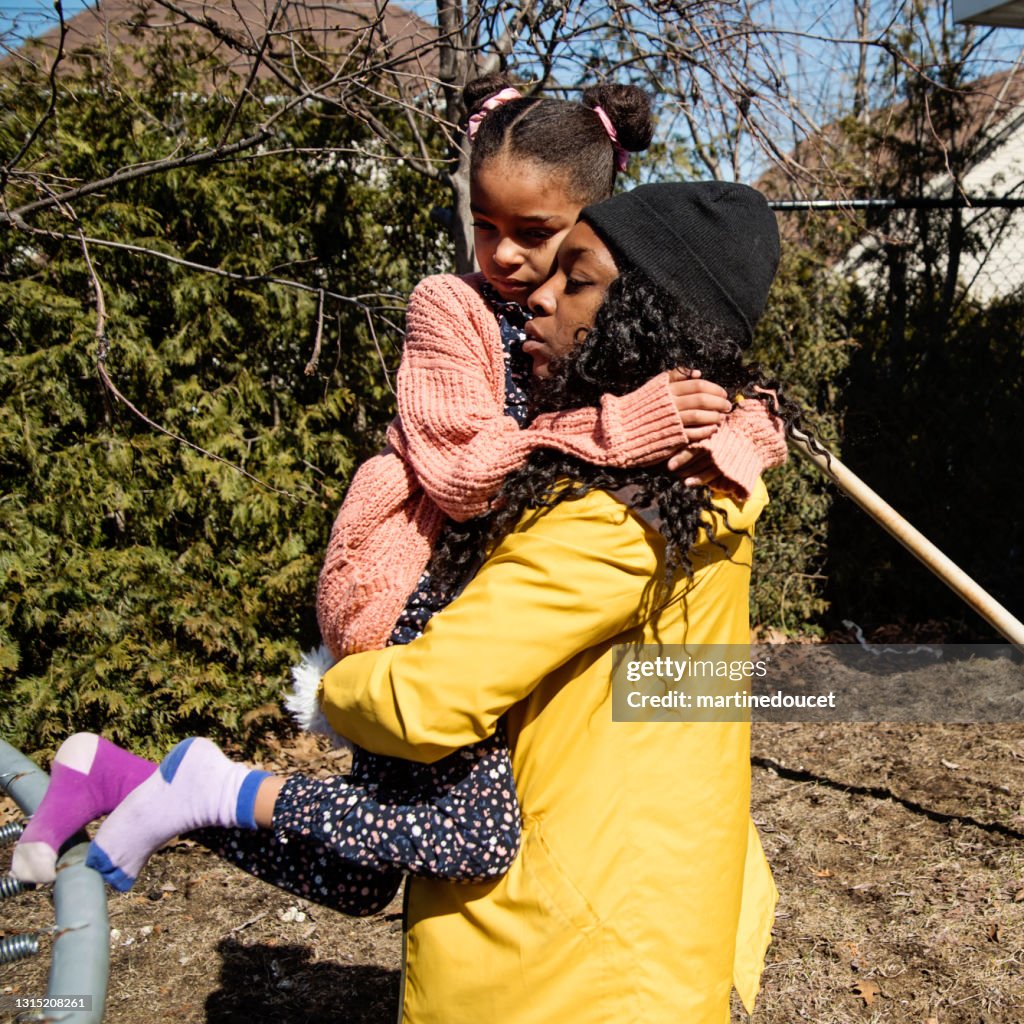 Madre consolando a su hija pequeña al aire libre en primavera.