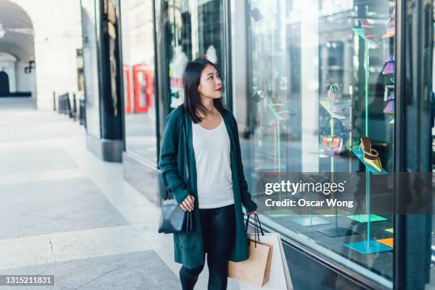 young woman window shopping on city street - window shopping stock pictures, royalty-free photos & images