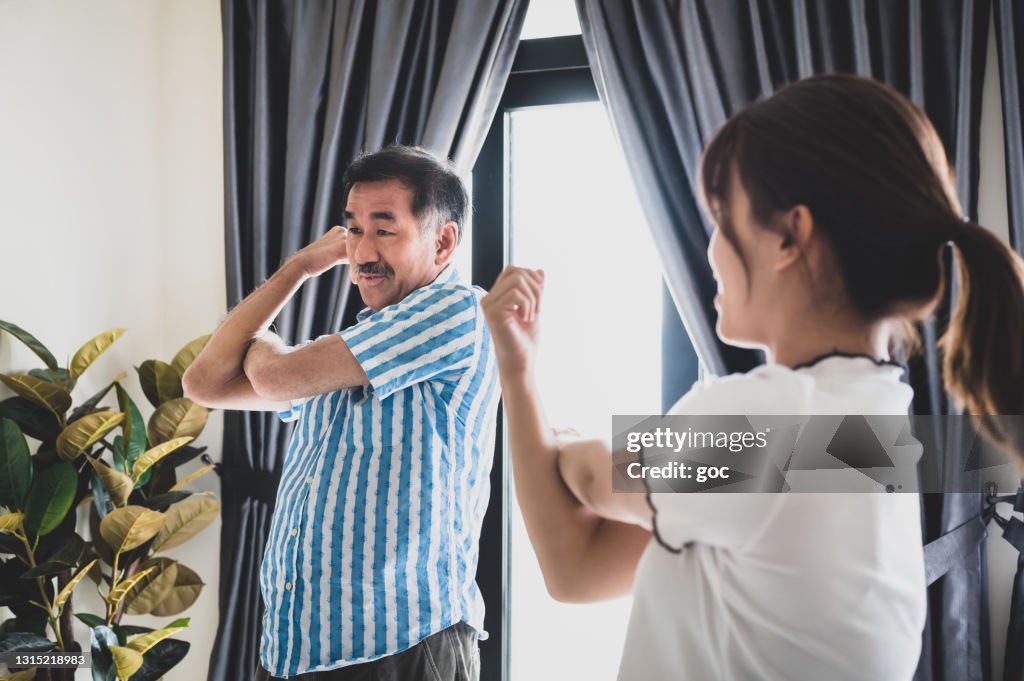 Glücklicher Senior chinese Mann tun Stretching-Übung mit Tochter im Wohnzimmer
