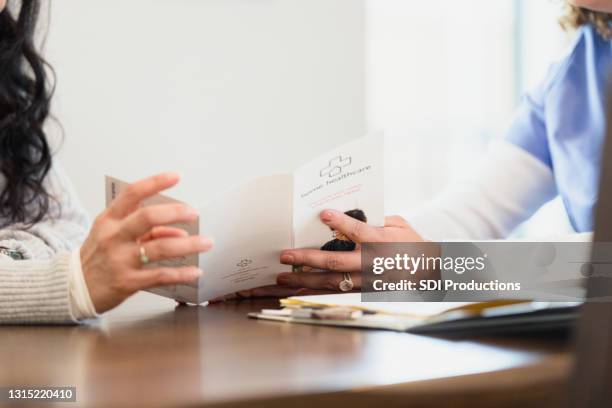 unrecognizable nurse discusses home healthcare with patient - blank pamphlet stock pictures, royalty-free photos & images