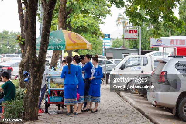 laotian women in blue traditional fashion are busing some food at street vendor - vientiane stock pictures, royalty-free photos & images