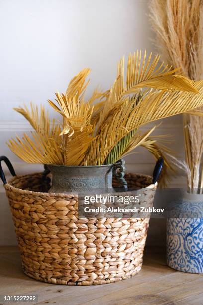 a large vase with dried flowers and branches in a wicker basket. modern, trendy and stylish, minimalistic living room interior. - wicker stock pictures, royalty-free photos & images
