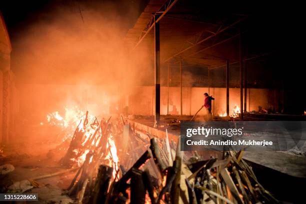 Workers can be seen at a crematorium where multiple funeral pyres are burning for patients who lost their lives to Covid-19 on April 29, 2021 in New...