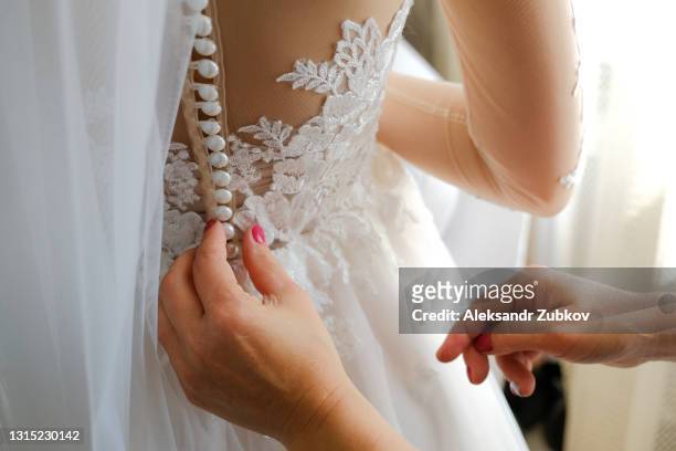 mom laces up the back of her daughter's openwork stylish wedding dress. morning preparations of the bride, support and care of the mother. - lace dress stock pictures, royalty-free photos & images