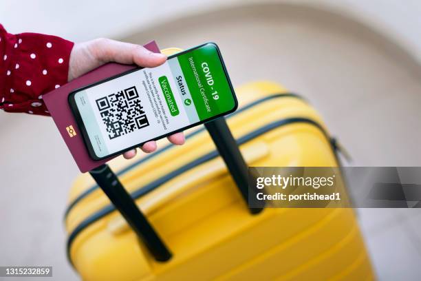 frau mit digitalen impfstoff pass app n handy für reisen - impfpass reisedokument stock-fotos und bilder