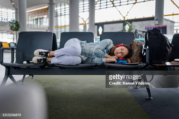 junge frau wartet auf verspäteten flug und schläft auf stühlen - cancel stock-fotos und bilder