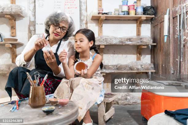 old woman teaching young girl painting crockery - pottery making stock-fotos und bilder