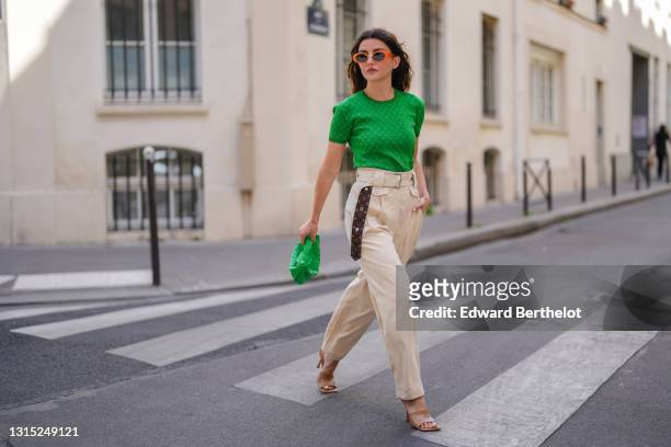 Alexandra Pereira wears orange sunglasses, a neon bold green Louis Vuitton t-shirt with printed monograms, neon bold green woven leather bag from...