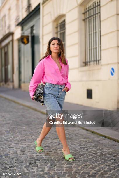 Alexandra Pereira wears a neon pink open oversized shirt from The Frankie Shop , a Dior Bobby monogram print bag, blue denim ripped shorts from Zara,...