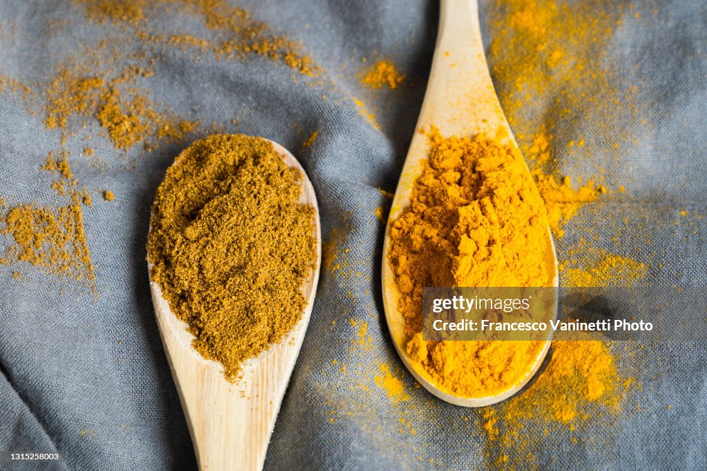 Curry and turmeric powder on wooden spoons.