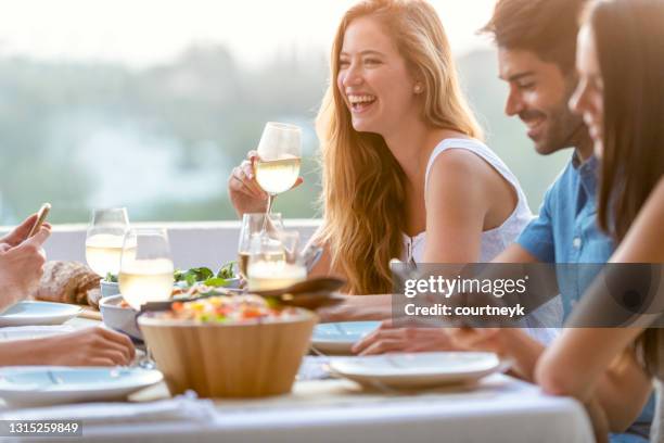 freunde plaudern und trinken auf einer dinnerparty mit weingläsern auf dem tisch. - weißwein stock-fotos und bilder