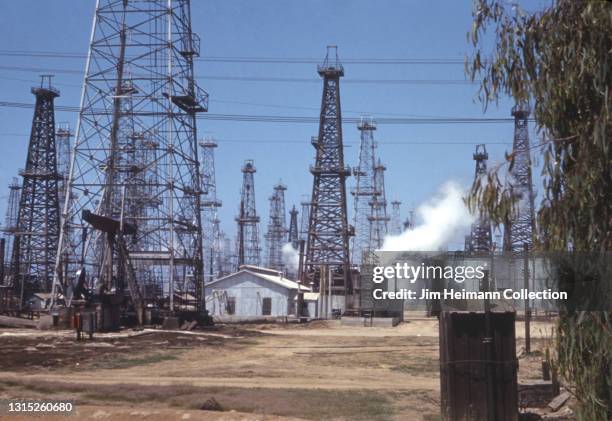 35mm film photo shows an oil refinery in Huntington Beach, California with oil derricks scattered across the dirt landscape, 1941.