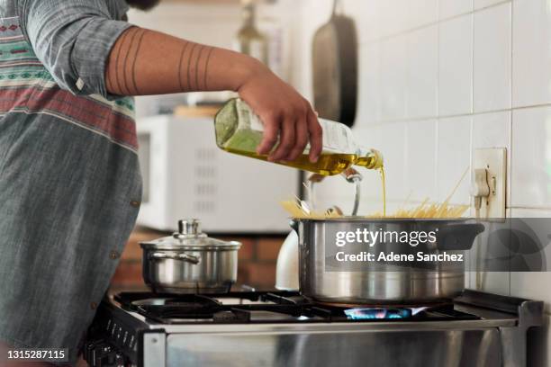 shot of an unrecognizable person cooking pasta in their kitchen - oil bottle stock pictures, royalty-free photos & images