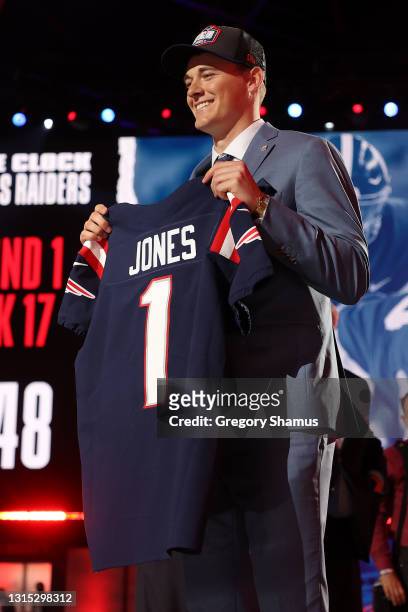 Mac Jones poses onstage after being selected 15th by the New England Patriots during round one of the 2021 NFL Draft at the Great Lakes Science...
