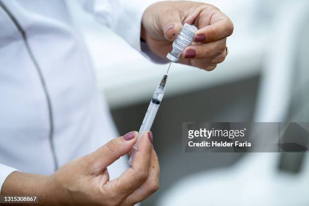 close up of covid-19 vaccine pull into syringe - vacinação stockfoto's en -beelden