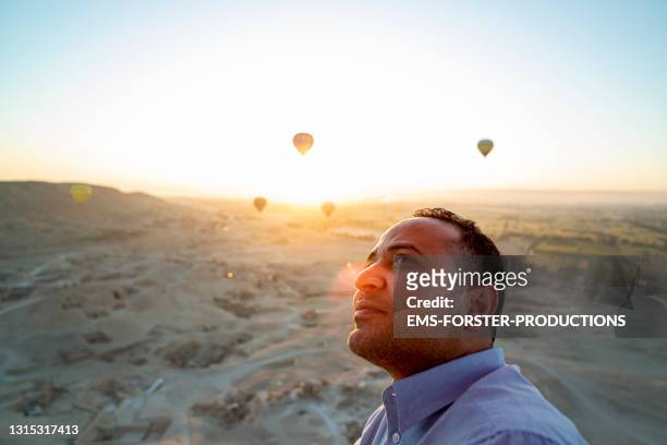 portrait of a egyptians standing in a hot air balloon ride early morning by the valley of the kings in luxor - black balloon stock-fotos und bilder