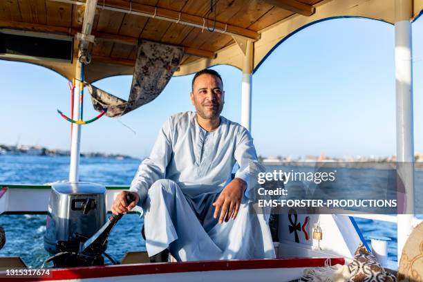 an egyptian man driving motorboat on nile river for tourists - nile river stock pictures, royalty-free photos & images