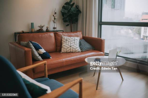 an interior of the residential building living room during day with coffee table, cushion on sofa - leather stock pictures, royalty-free photos & images
