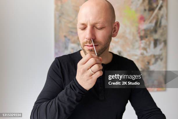 男性は、抗原検査または迅速なコロナ検査のために鼻綿棒を取り、彼の目を閉じる - 綿棒 ストックフォトと画像