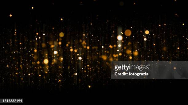 defocused golden particles glittery against dark background with copy space. christmas overlay - shine imagens e fotografias de stock
