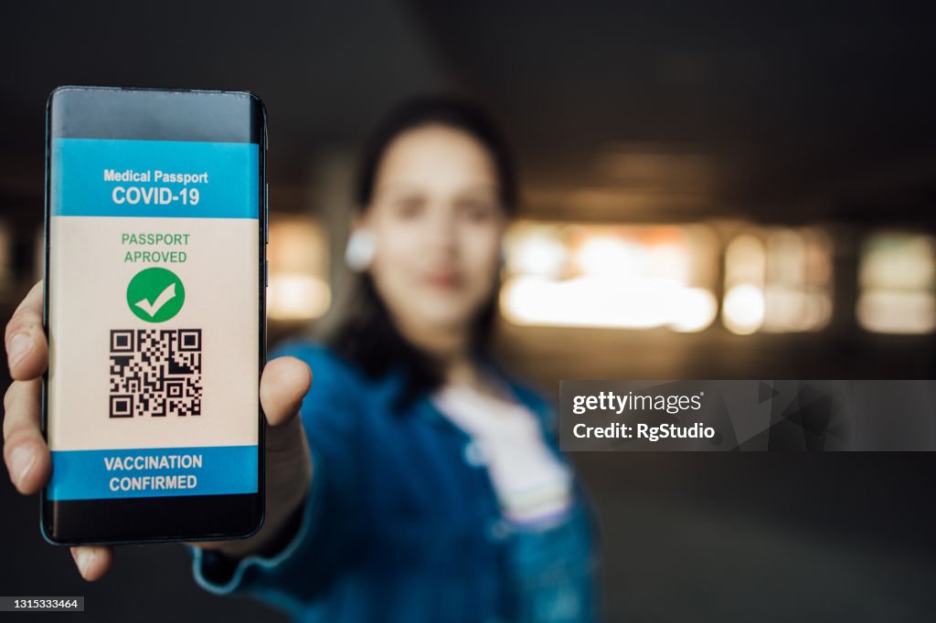 Young woman showing a digital vaccine certificate on her smartphone